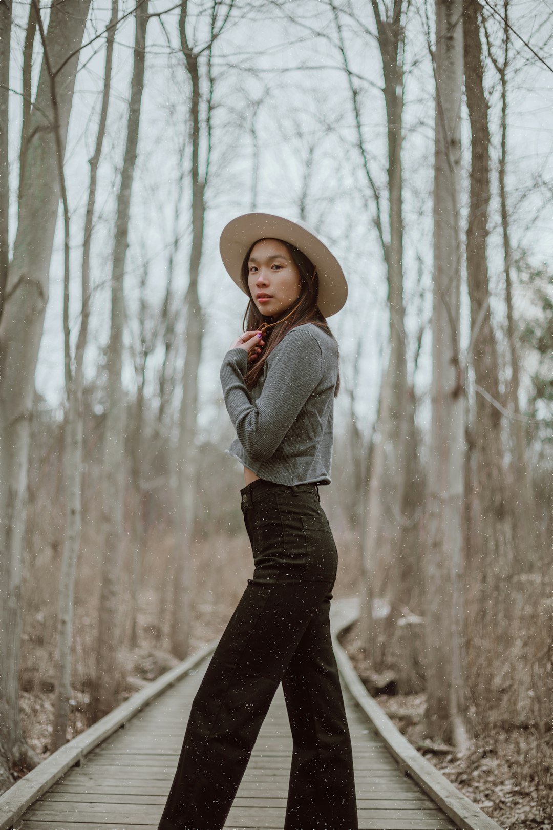 woman in gray long sleeve shirt and black skirt standing on forest during daytime