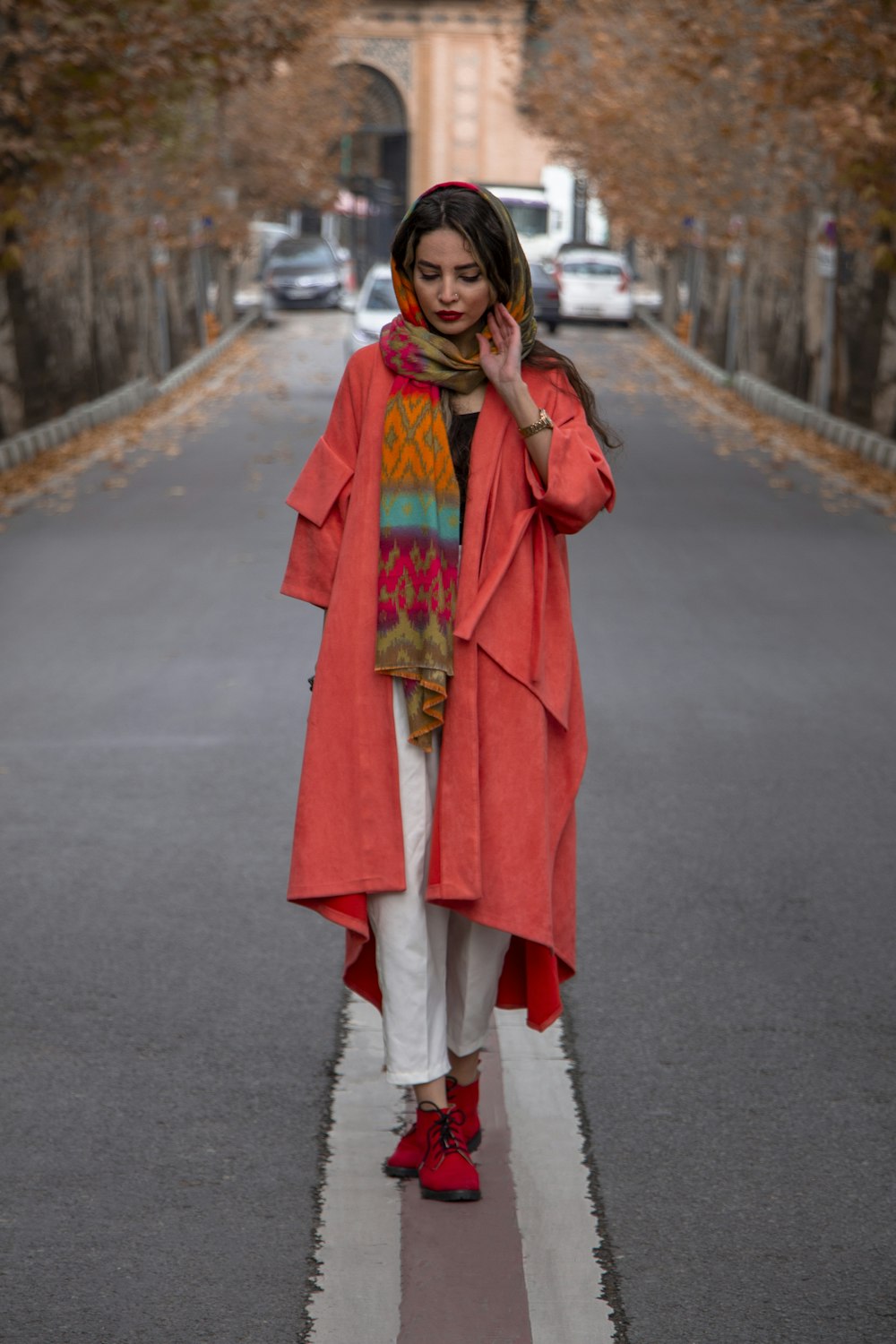 woman in red coat standing on road during daytime