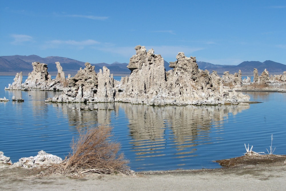 gray rock formation beside body of water under blue sky during daytime