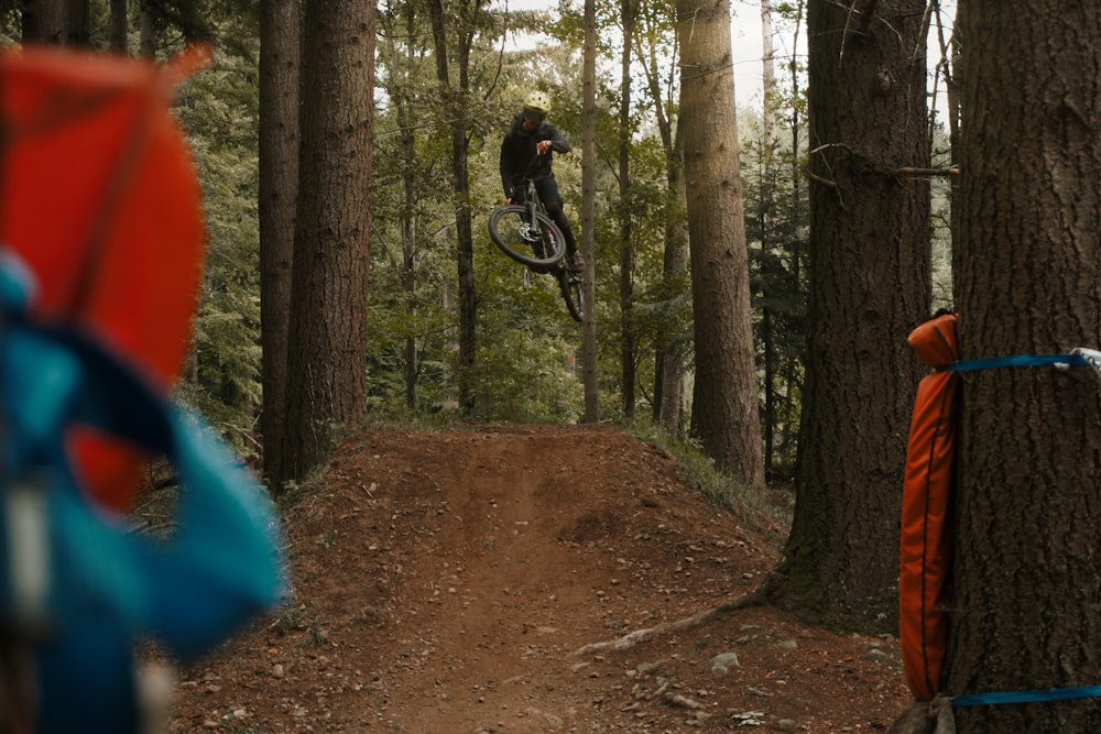 man in black jacket riding bicycle on forest during daytime