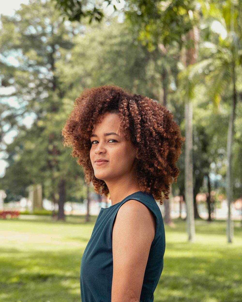 woman in blue sleeveless shirt standing near trees during daytime