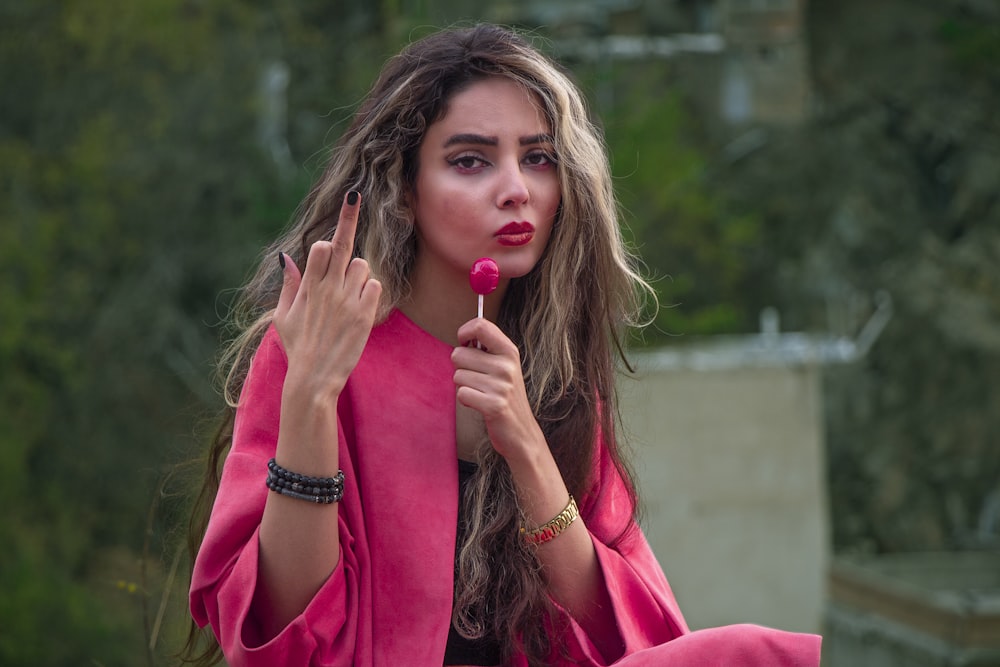 woman in red long sleeve shirt holding lollipop