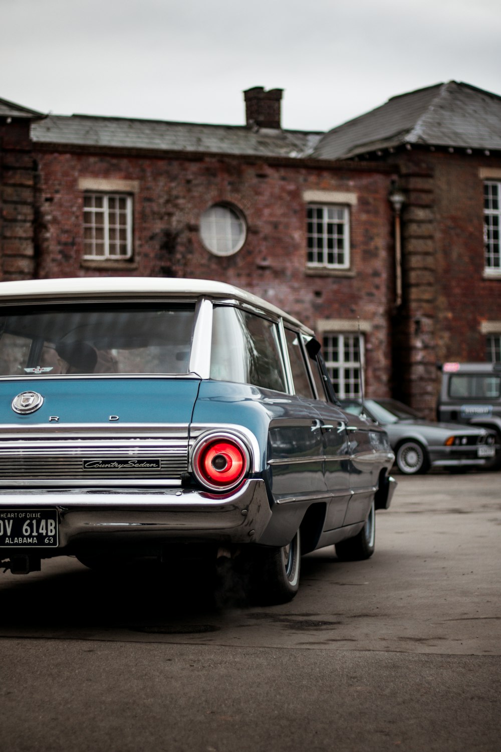 blue and white car parked beside brown brick building during daytime