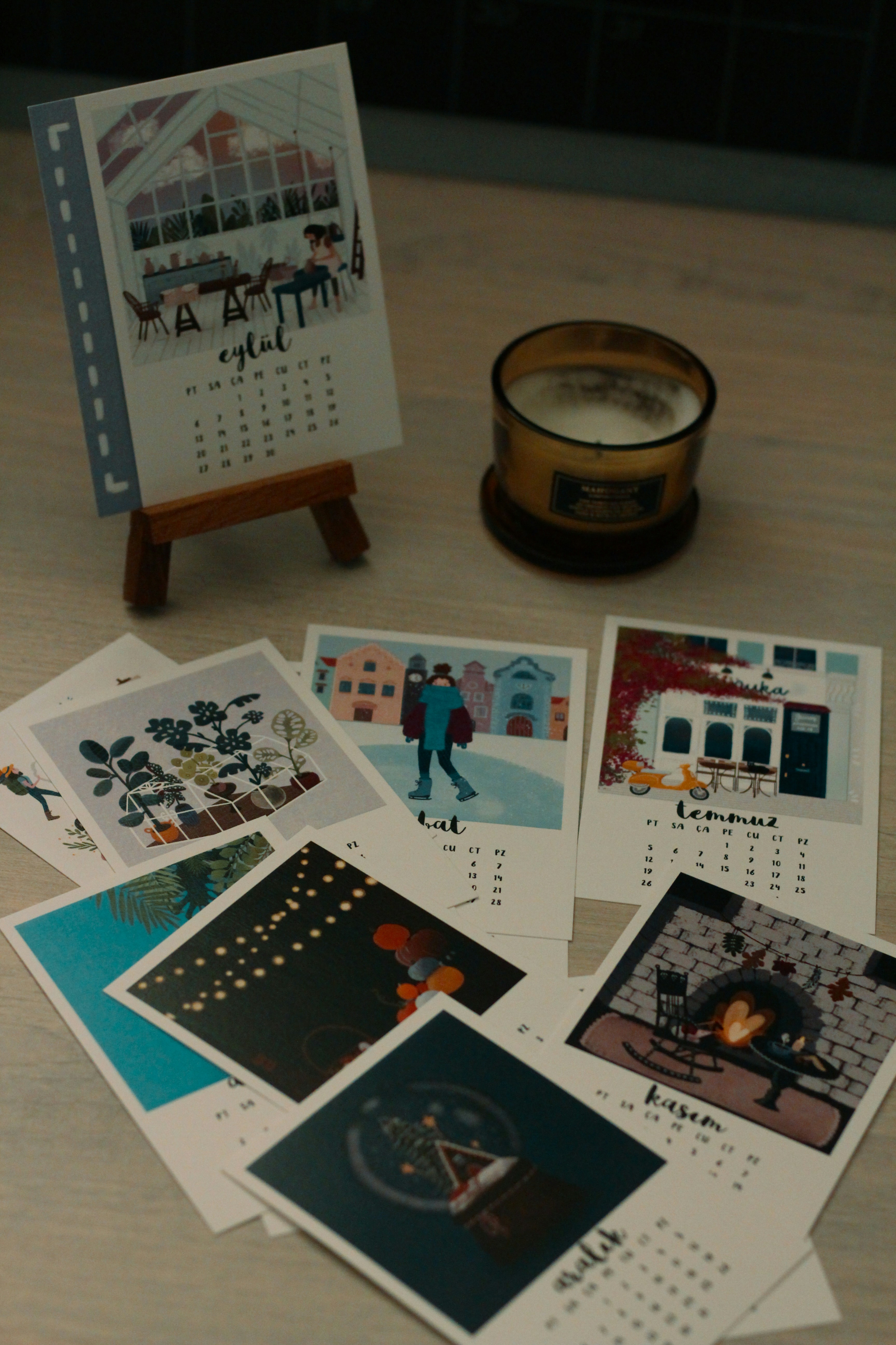 Printed calendar pages with vibrant photography laid flat on a wooden table