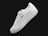 A single white sneaker with a sleek design, featuring subtle perforations along the side for ventilation. The sneaker has a classic lace-up style and branding visible on the side and heel. It is positioned at an angle against a plain black background.