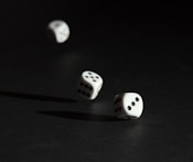 3 white dice on black surface