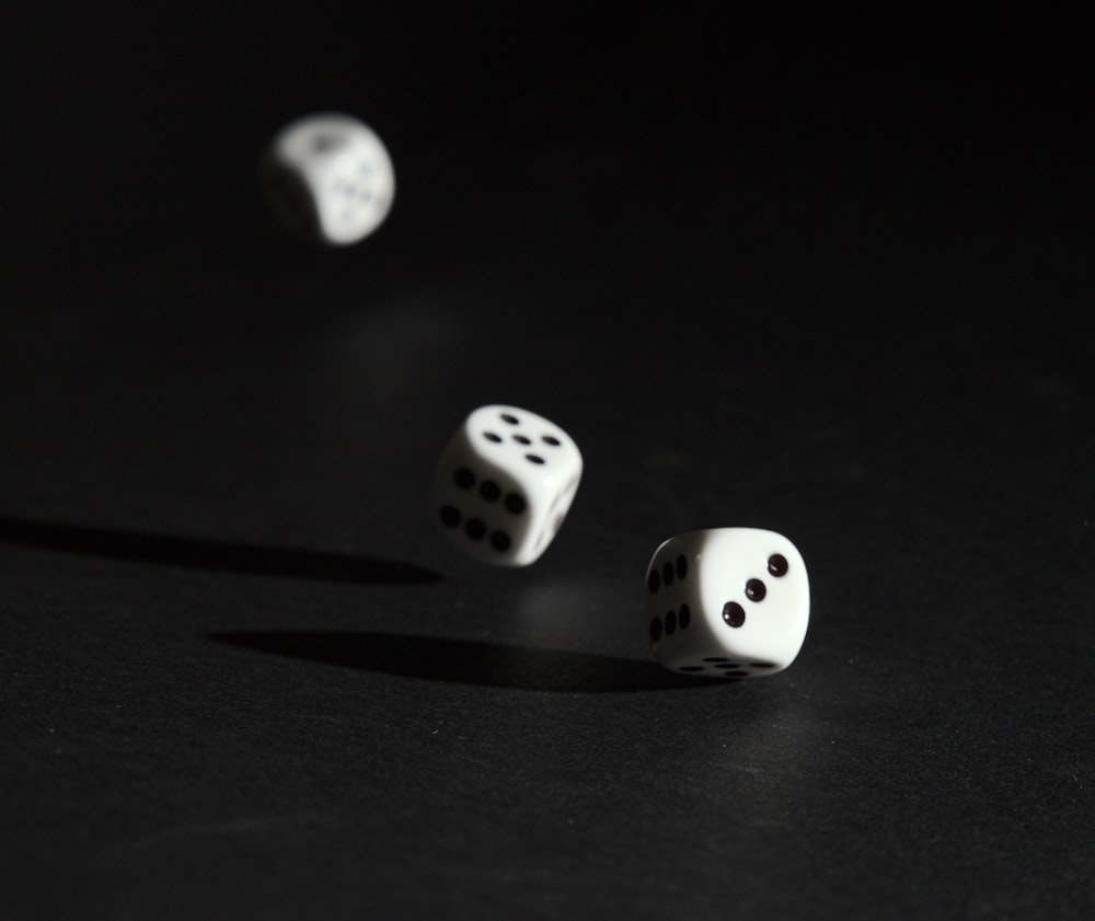 3 white dice on black surface