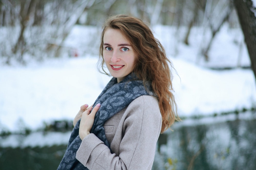 woman in gray coat standing on snow covered ground during daytime