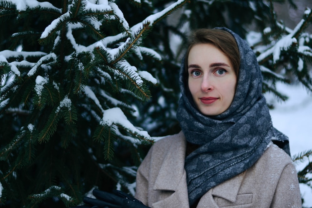 woman in gray coat standing near green pine tree