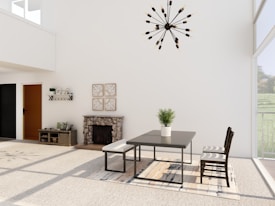A modern dining room with minimalist decor features a sleek table and chairs on a large patterned rug. A potted plant sits centered on the table. The room is well-lit with large windows allowing natural light to enter. A stylish chandelier hangs from the ceiling. A stone fireplace, small console table, and decorative wall art complete the design.
