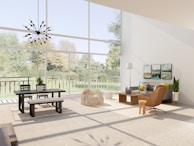 An inviting, sunlit living room featuring high-end furnishings and floor-to-ceiling windows overlooking a manicured garden.