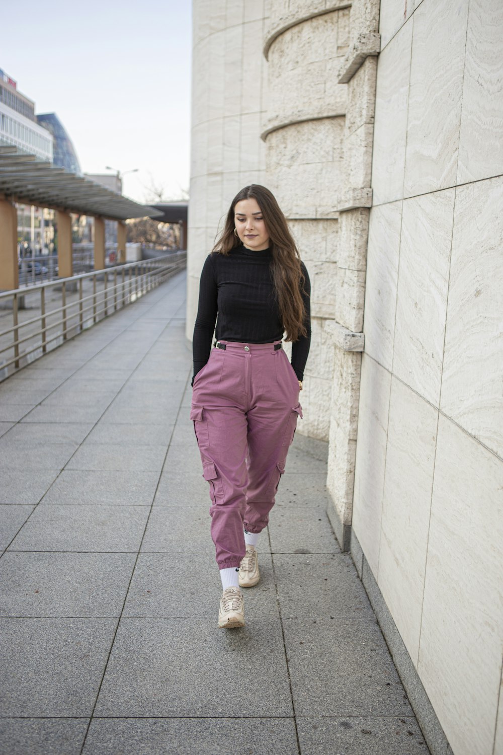 woman in black long sleeve shirt and pink pants standing on gray concrete floor during daytime