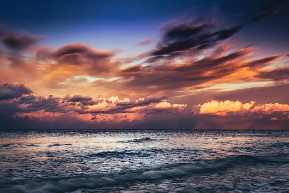 body of water under cloudy sky during sunset