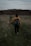 woman in yellow jacket and black pants walking on green grass field during daytime