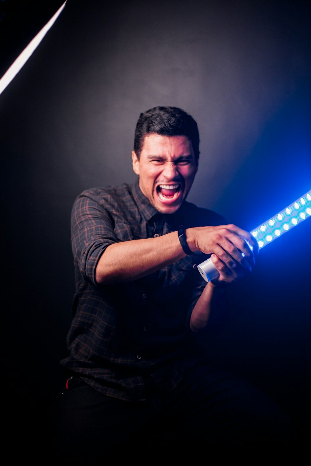 man in black crew neck t-shirt holding blue flashlight