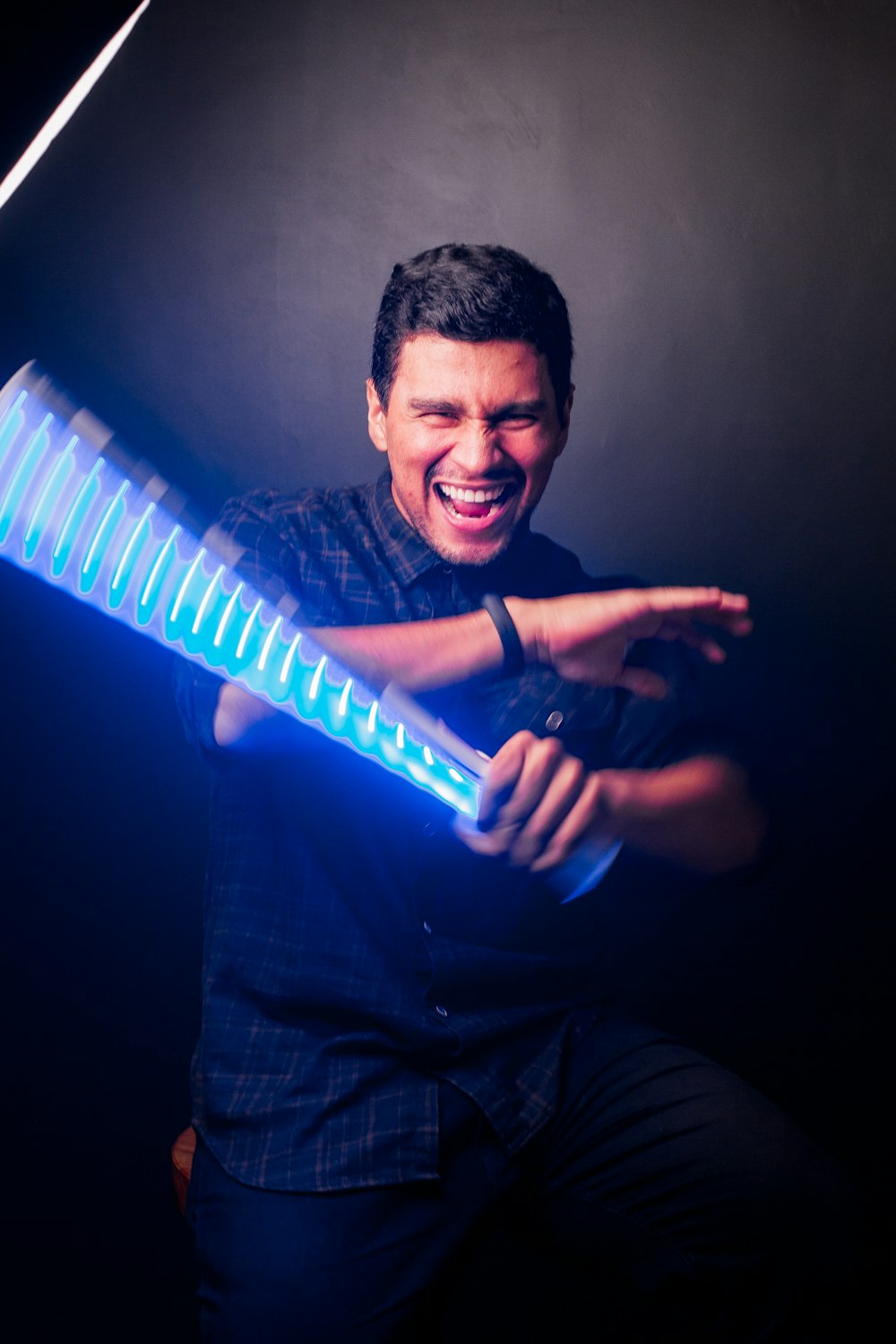 man in black dress shirt holding blue and white striped tube