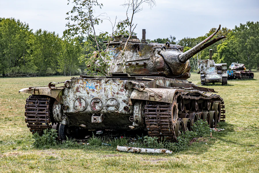 An abandoned, overgrown tank standing in a grass field