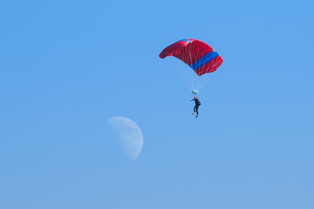 person in black jacket and black pants riding red and yellow parachute