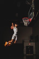A basketball player dunking a ball into a hoop in a dark gym