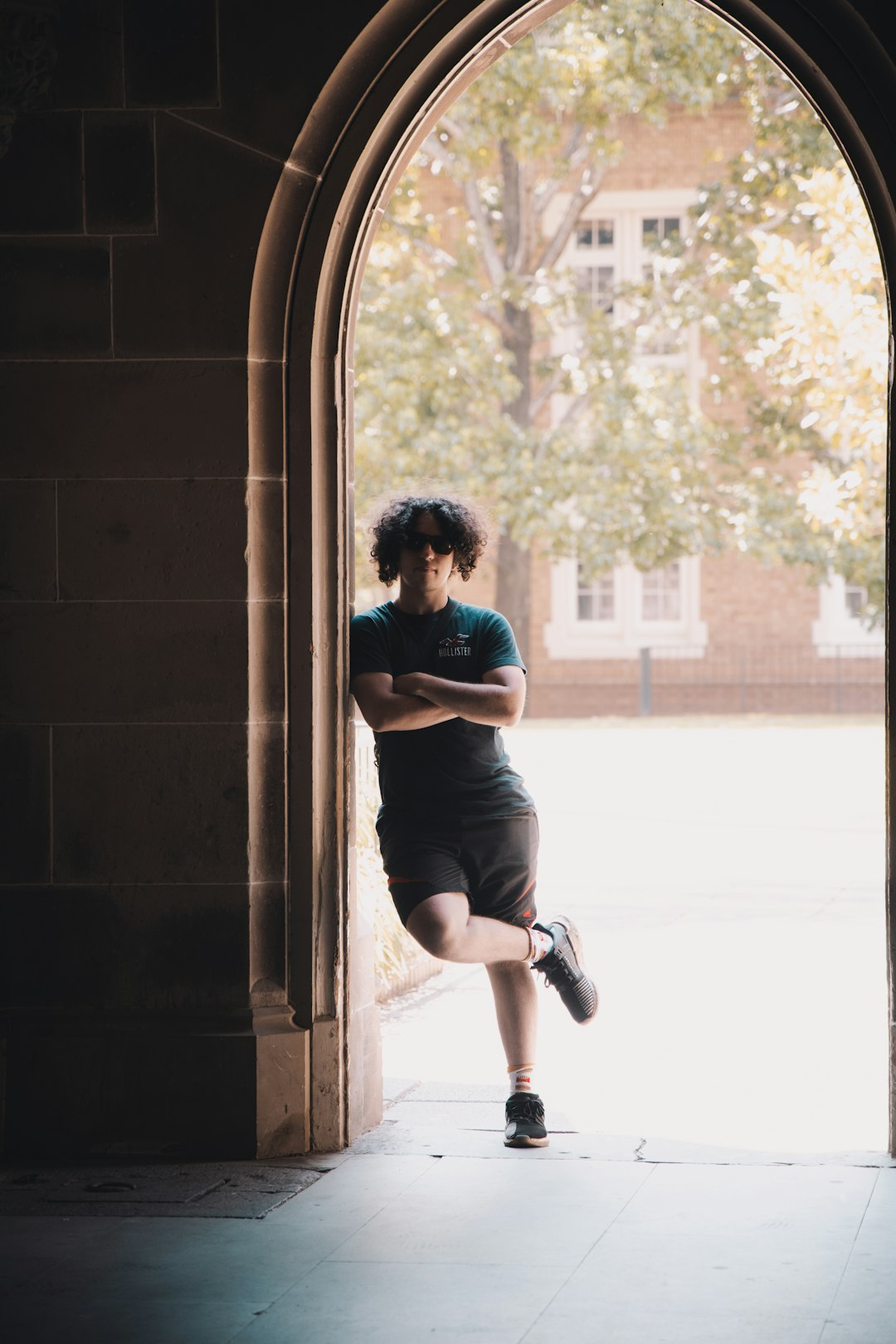 woman in blue t-shirt and black shorts sitting on window during daytime