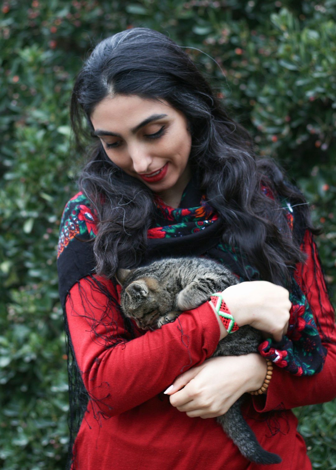 woman in red long sleeve shirt holding brown tabby cat