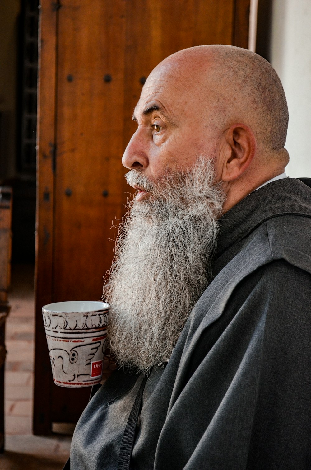 man in black coat sitting beside brown wooden wall