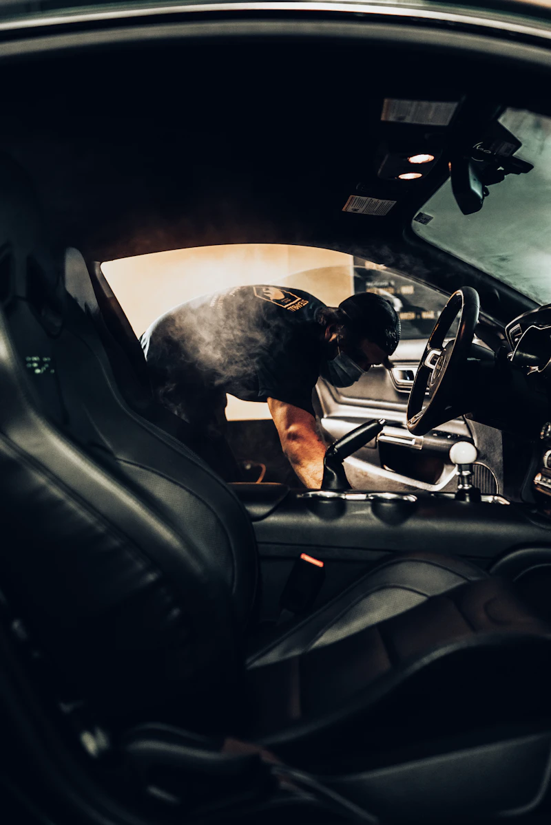 Technician steam-cleaning the interior and dash of a sports car