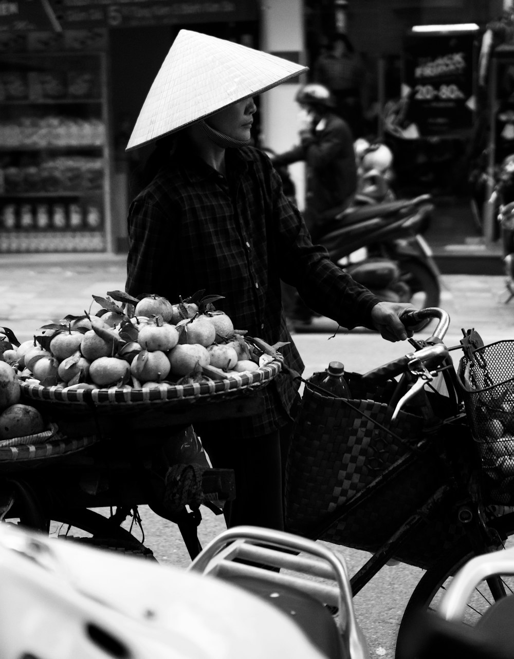 grayscale photo of woman in black jacket and white umbrella standing on sidewalk with fruits on on on on on