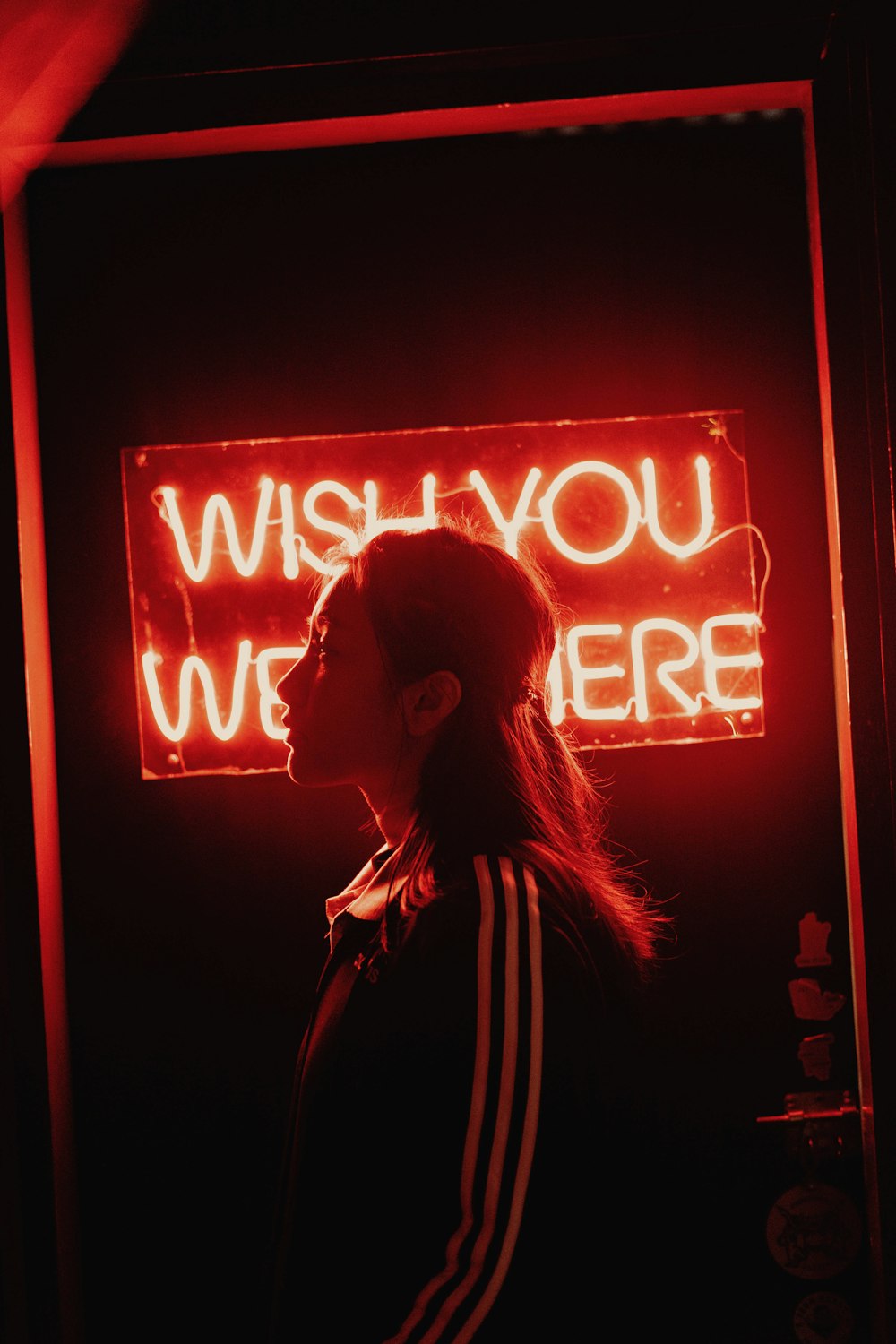 woman in white jacket standing in front of red and white neon signage
