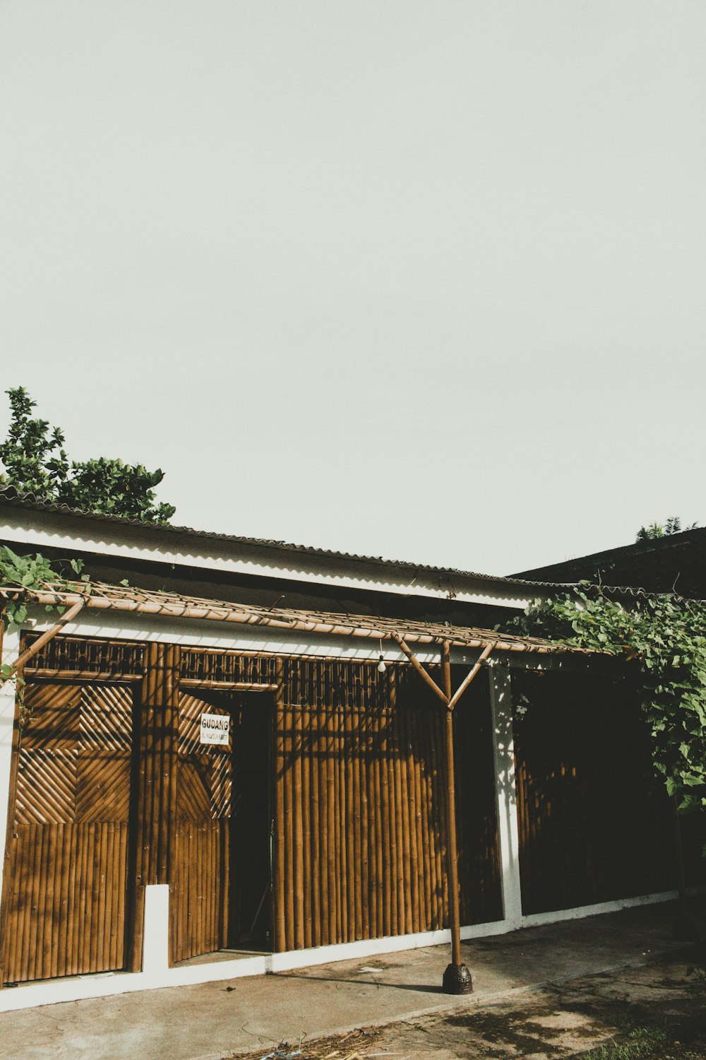 昼間は緑の木々のそばの茶色い木造住宅