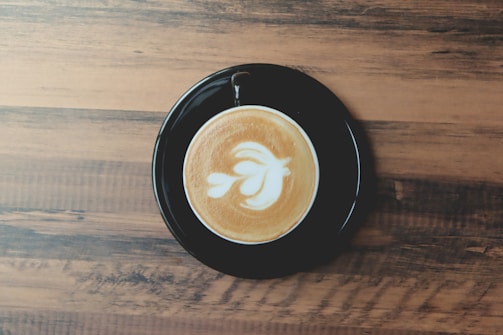 Artistic coffee cup with floral latte art on a wooden table.