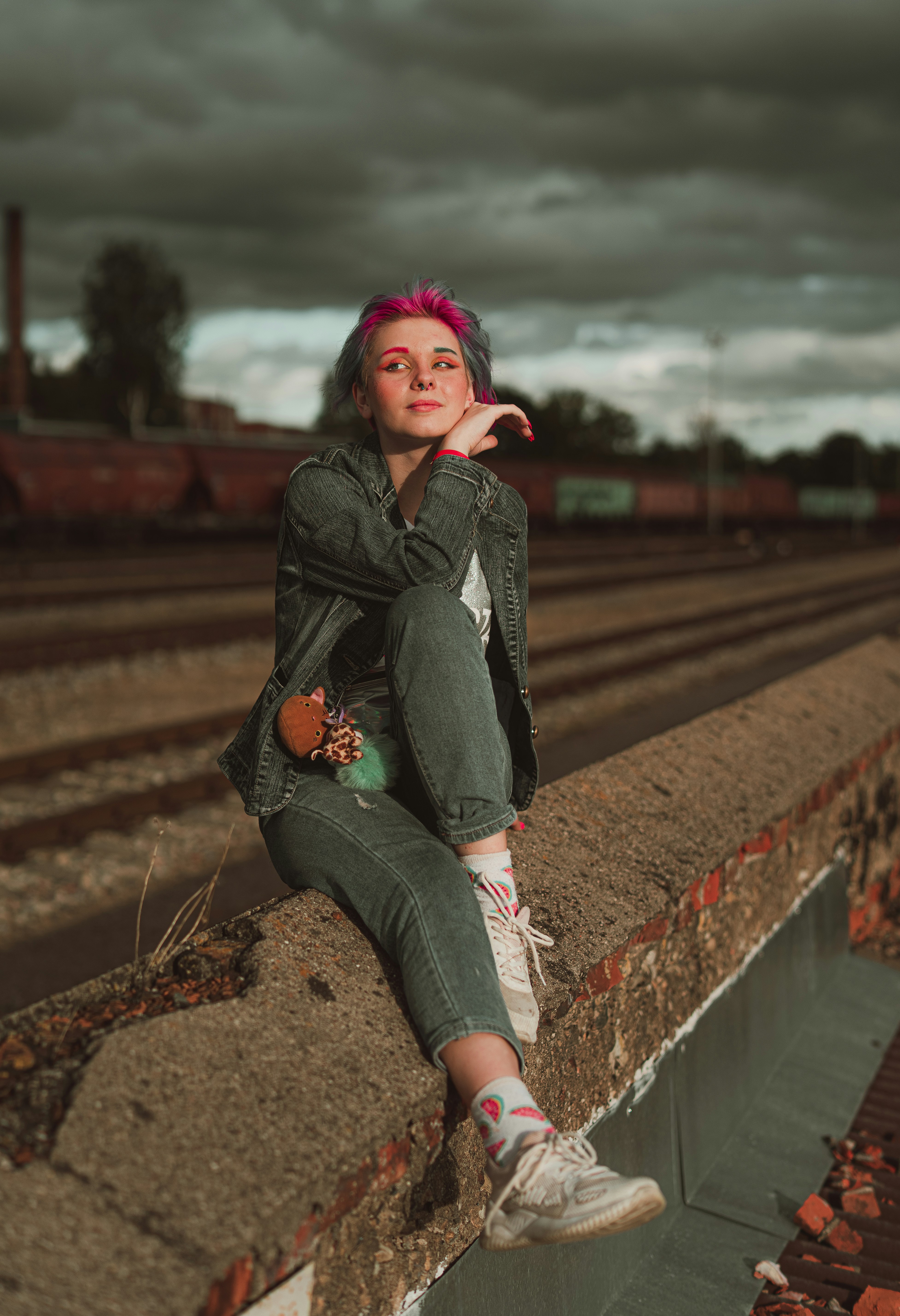 Woman in black leather jacket sitting on train rail during daytime ...