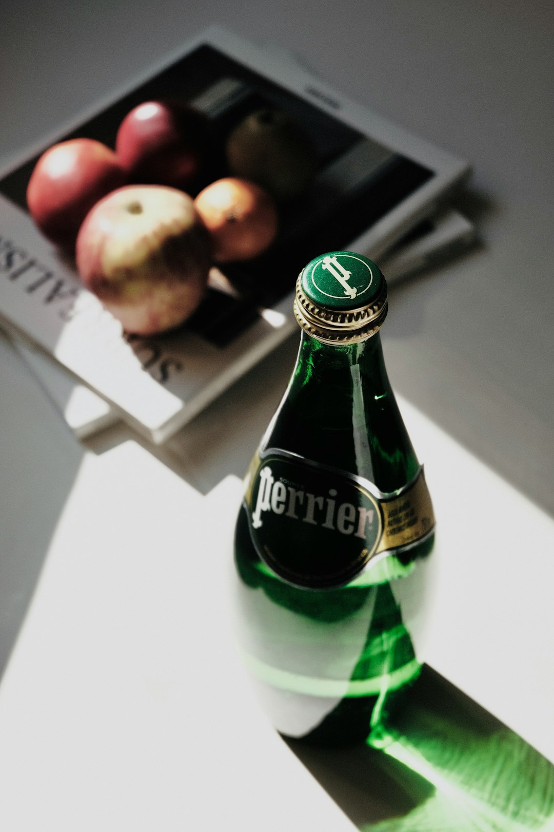 green glass bottle on white table