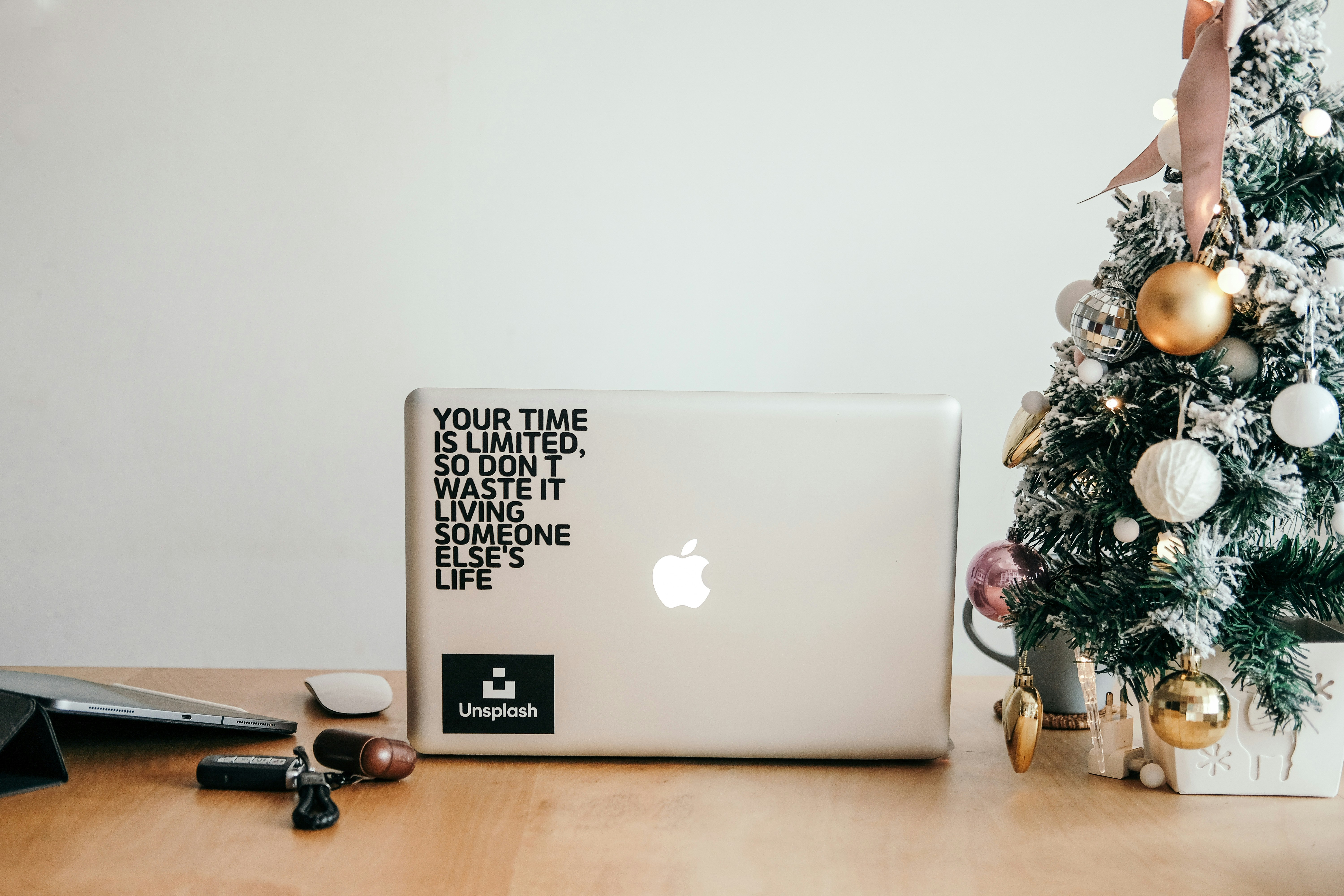 茶色の木製のテーブルの上に黒いフレームの眼鏡の横に銀色のMacBook