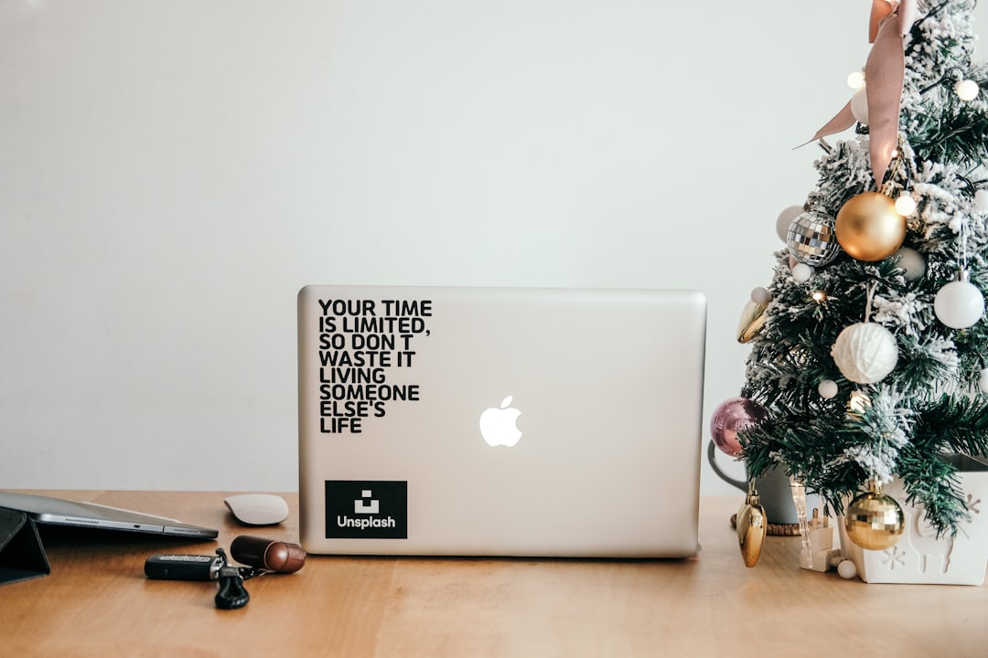 silver macbook beside black framed eyeglasses on brown wooden table