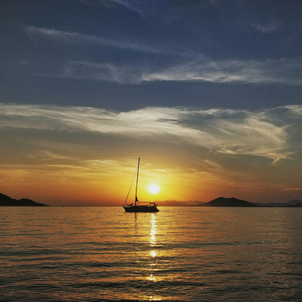 silhouette of boat on sea during sunset