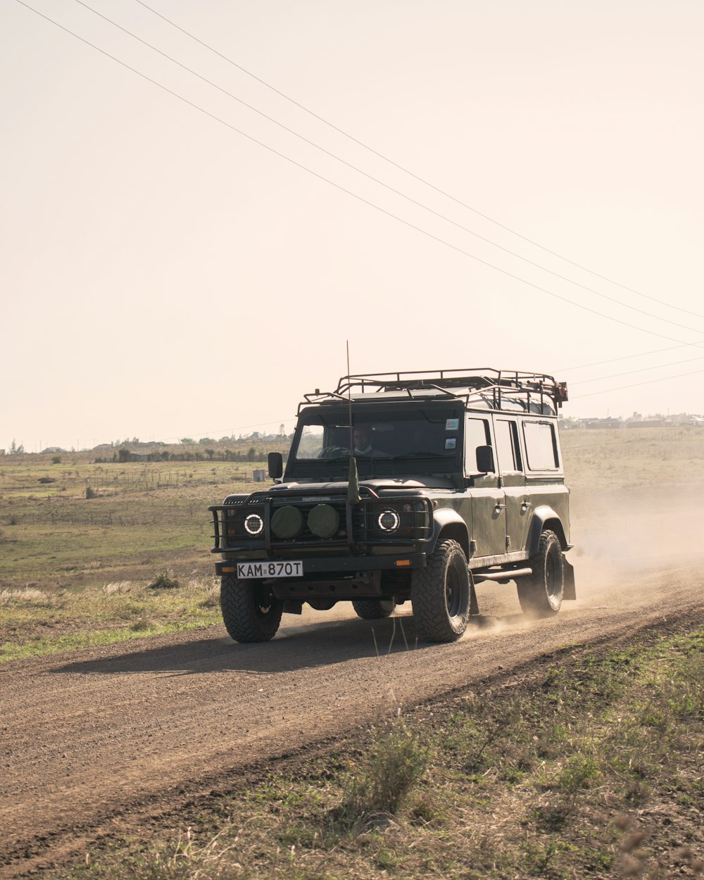 昼間の未舗装の道路に黒いSUV