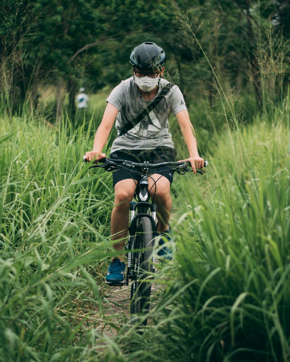 homem na camiseta cinza que monta a bicicleta no campo de grama verde durante o dia