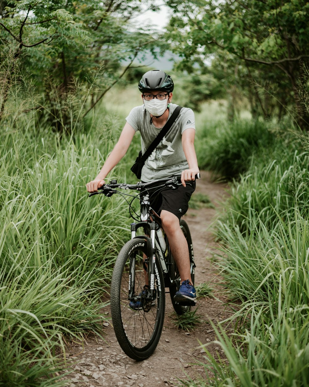 man in gray tank top riding bicycle on green grass field during daytime