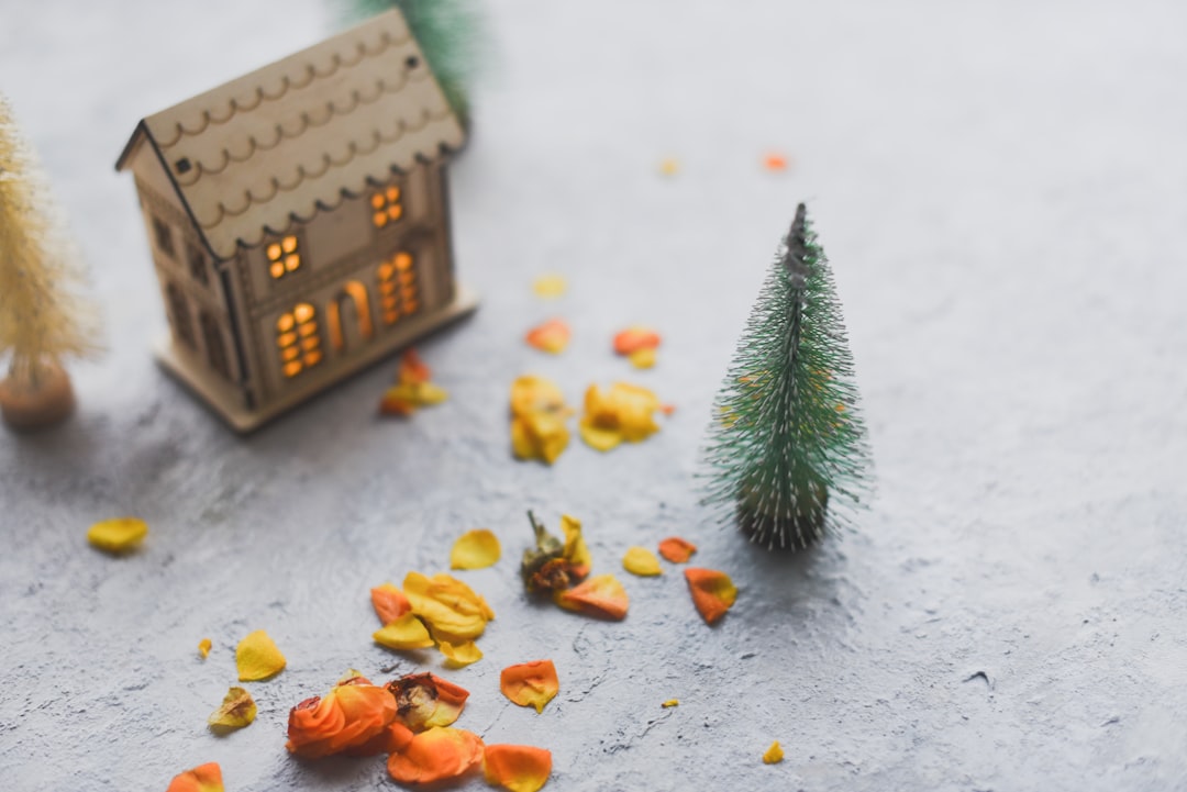 brown wooden house miniature beside green pine tree