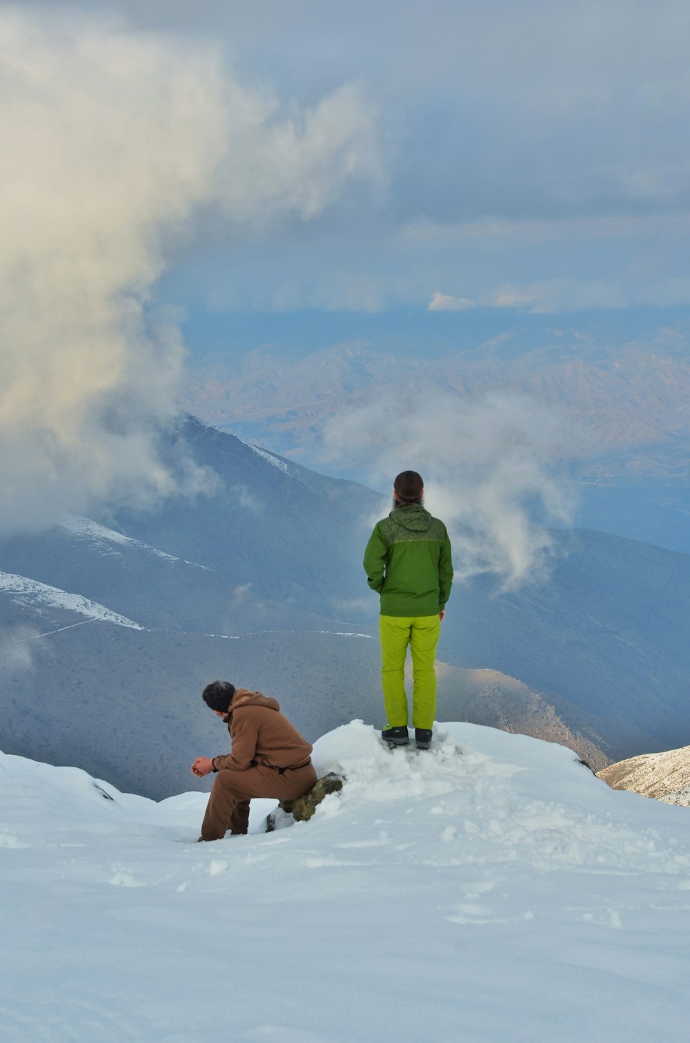 man in green jacket sitting on snow covered ground during daytime