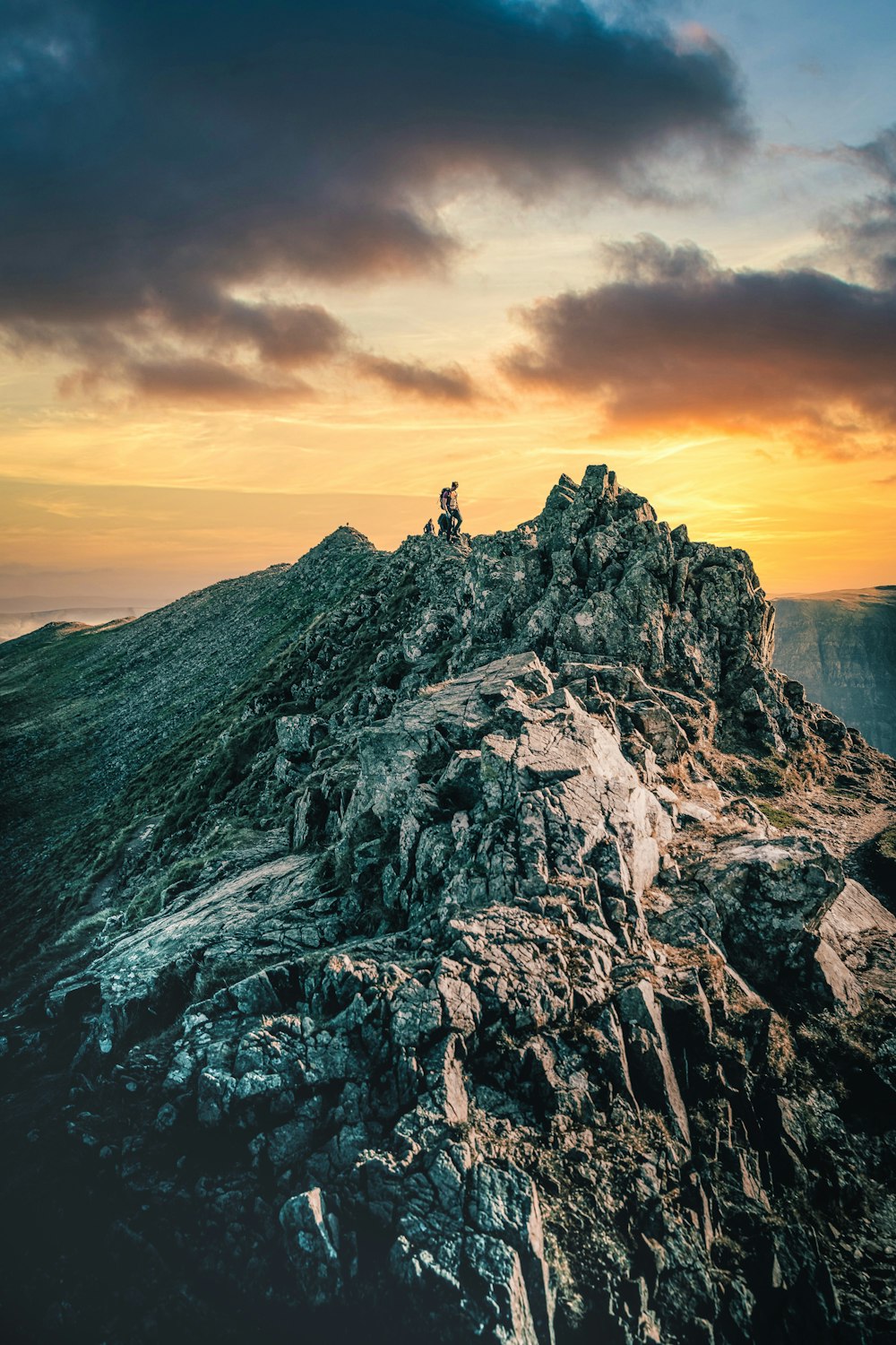 person standing on rocky mountain during sunset