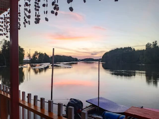 A cozy band setup on a wooden dock at sunset, with soft glowing lights reflecting on calm water.