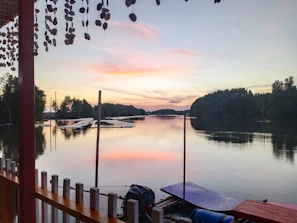 Private lakeside dock at sunset with a canoe tied up and gentle ripples on the water