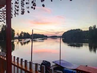 A peaceful lakeside dock at sunset, with gentle ripples and a lone canoe tied up.