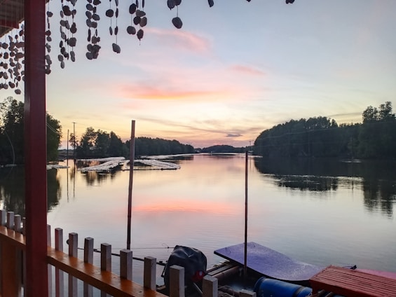 A serene view of a wooden dock at sunset on Lac Etchemin, with a boat gently moored.
