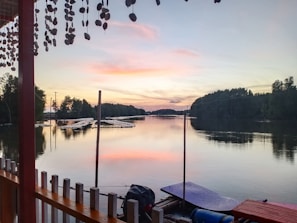 A peaceful lakeside scene at sunset with a small rowboat tied to a simple dock.
