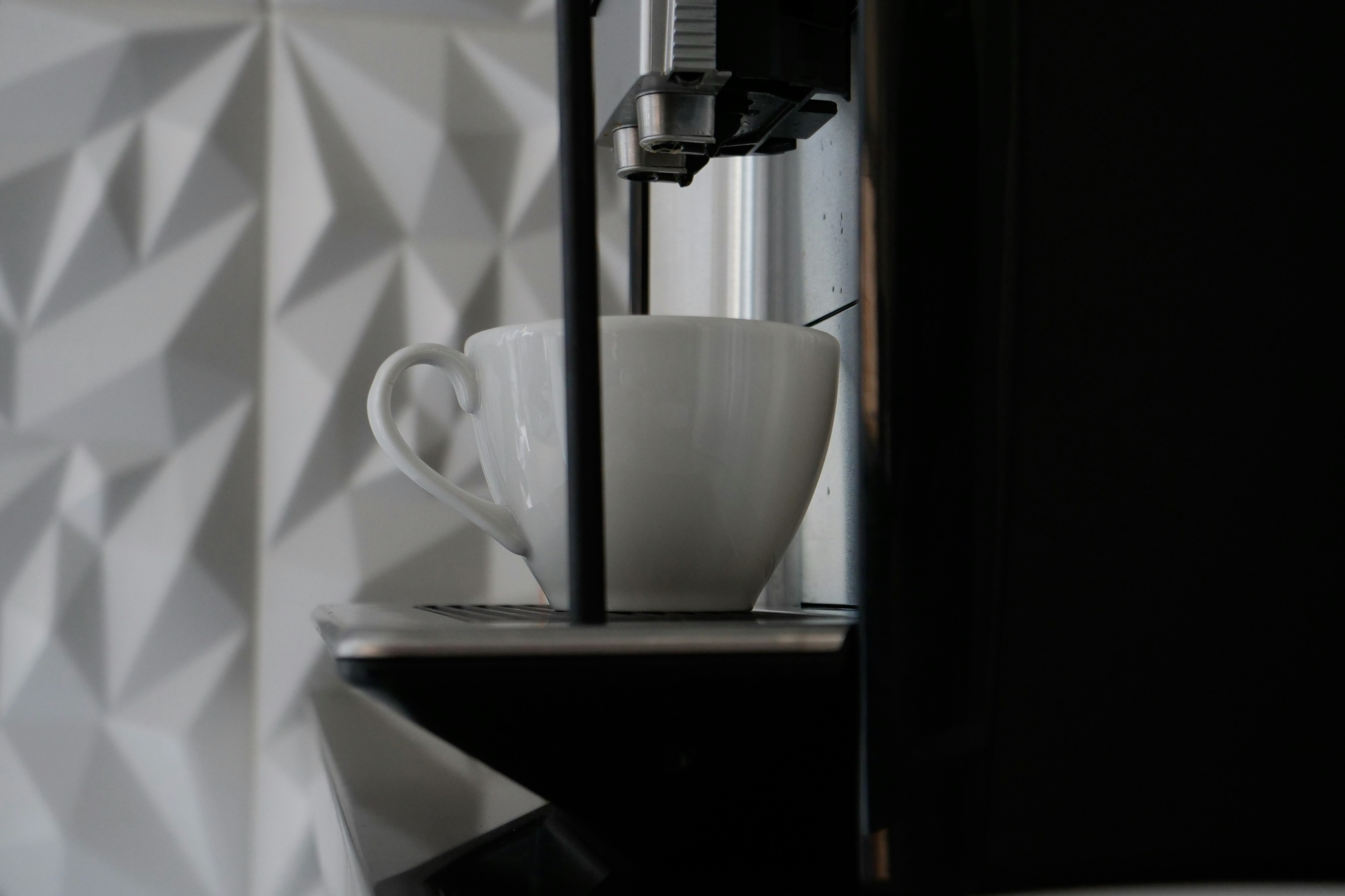 Taza de cerámica blanca en cafetera negra y plateada