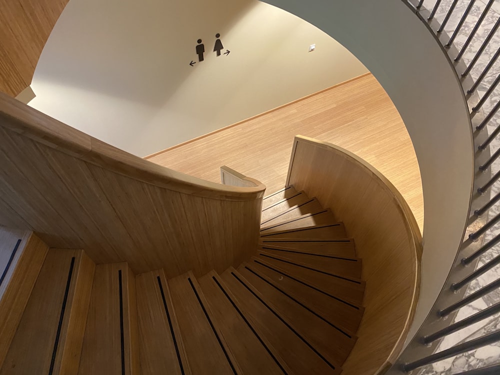 Escalera de caracol de madera marrón con pared blanca