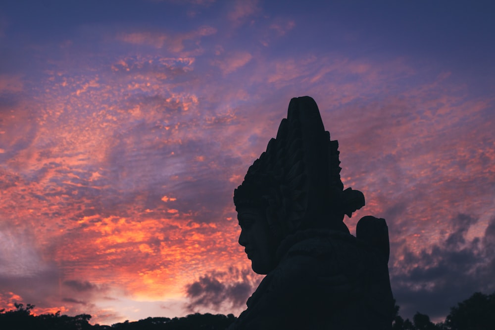 silhouette of person under cloudy sky during sunset